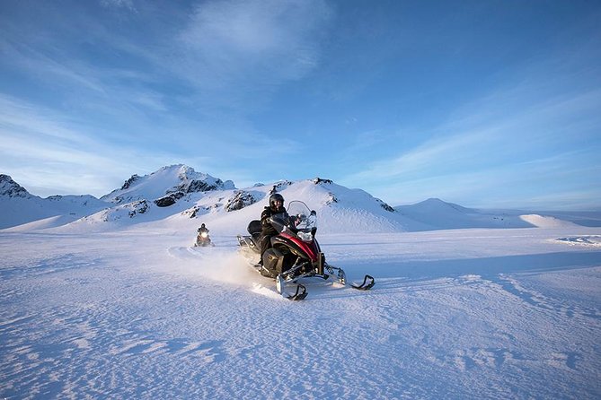 A snowmobile rider crossing Langjökull below mountain peaks